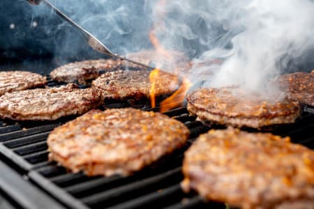 A closeup of the juicy burger meat being grilled on the grill