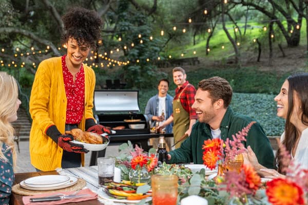 Friends and family enjoying outdoor backyard grilling and dining around a Nexgrill barbecue grill