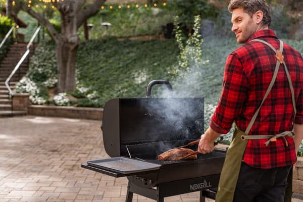 Friends and family enjoying outdoor backyard grilling and dining around a Nexgrill barbecue grill