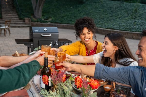 Friends and family enjoying outdoor backyard grilling and dining around a Nexgrill barbecue grill