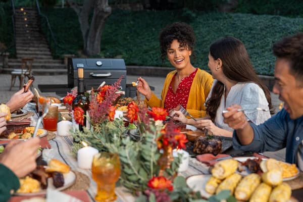 Friends and family enjoying outdoor backyard grilling and dining around a Nexgrill barbecue grill